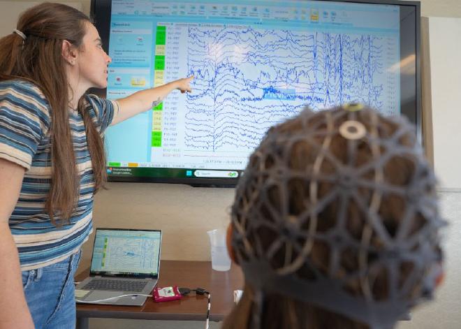 Una investigadora señala el progreso en la exploración cerebral de Aimee Kain luego de su participación en el programa de terapia de baile de ocho semanas para tratar los efectos secundarios del cáncer. Crédito: The Ohio State University Comprehensive Cancer Center