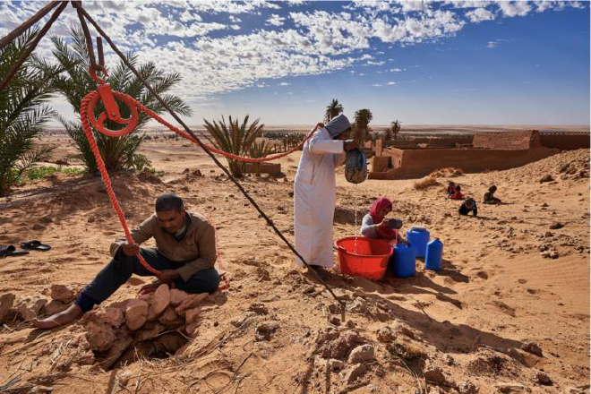 En el corazón del desierto, un grupo de personas trabaja en conjunto para extraer agua de un pozo tradicional mediante un sistema de poleas manuales. Crédito de la imagen: Abdallah Khalili / CNULD