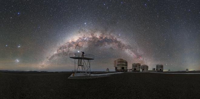 Los cielos oscuros sobre el Observatorio Paranal de ESO, hogar del Very Large Telescope (VLT) de ESO, ofrecen vistas impresionantes, tan claras y tan llenas de estrellas que casi se pueden tocar. De pie sobre una plataforma en el VLT, el embajador fotográfico de ESO, Petr Horálek, se acerca a un objeto destacado en el cielo. Se podría suponer que este cuerpo brillante, como muchos otros en el cielo, es una estrella, pero en realidad es un planeta de nuestro Sistema Solar: el gigante gaseoso Júpiter. Más cerca de la Tierra, se pueden ver al fondo los cuatro telescopios unitarios (UT) que componen el VLT. Cada UT cuenta con un espejo de 8,2 metros y funcionan de forma sinérgica para producir algunas de las imágenes más nítidas del Universo. Junto a los cuatro UT hay cuatro telescopios auxiliares (AT) móviles más pequeños que tienen espejos de 1,8 metros. The Chilean Atacama desert once again proves its value as the ideal location for ESO’s VLT. The remoteness of the observatory means that there is very little to no light pollution, which is vital for astronomy and also yields such breathtaking views. Crédito: ESO/<a href="https://www.facebook.com/PetrHoralekPhotography"   target="_blank">
    P. Horálek</a>