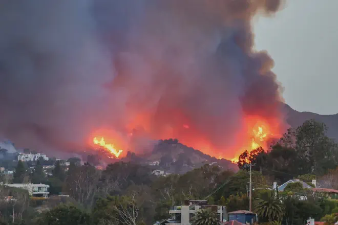 El humo y las llamas del incendio de Palisades inundan el cielo, como se ve desde el barrio de Pacific Palisades en Los Ángeles. (Crédito: Tiffany Rose/Getty Images)