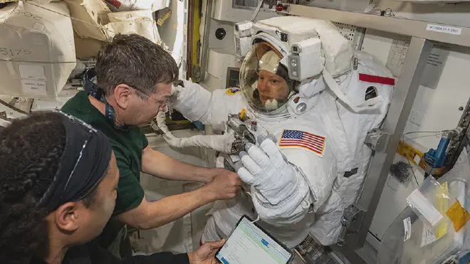 Los astronautas Jeanette Epps y Mike Barratt ayudan a su colega Tracy C. Dyson, enfundada en su traje espacial, durante una revisión rutinaria